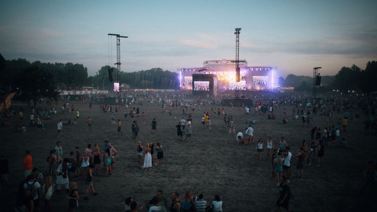 Foule de spectateurs devant une scène de concert éclairée par des projecteurs.