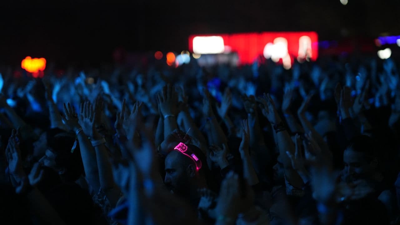 Vue sur une salle de concert plongée dans la pénombre, scène illuminée au fond.