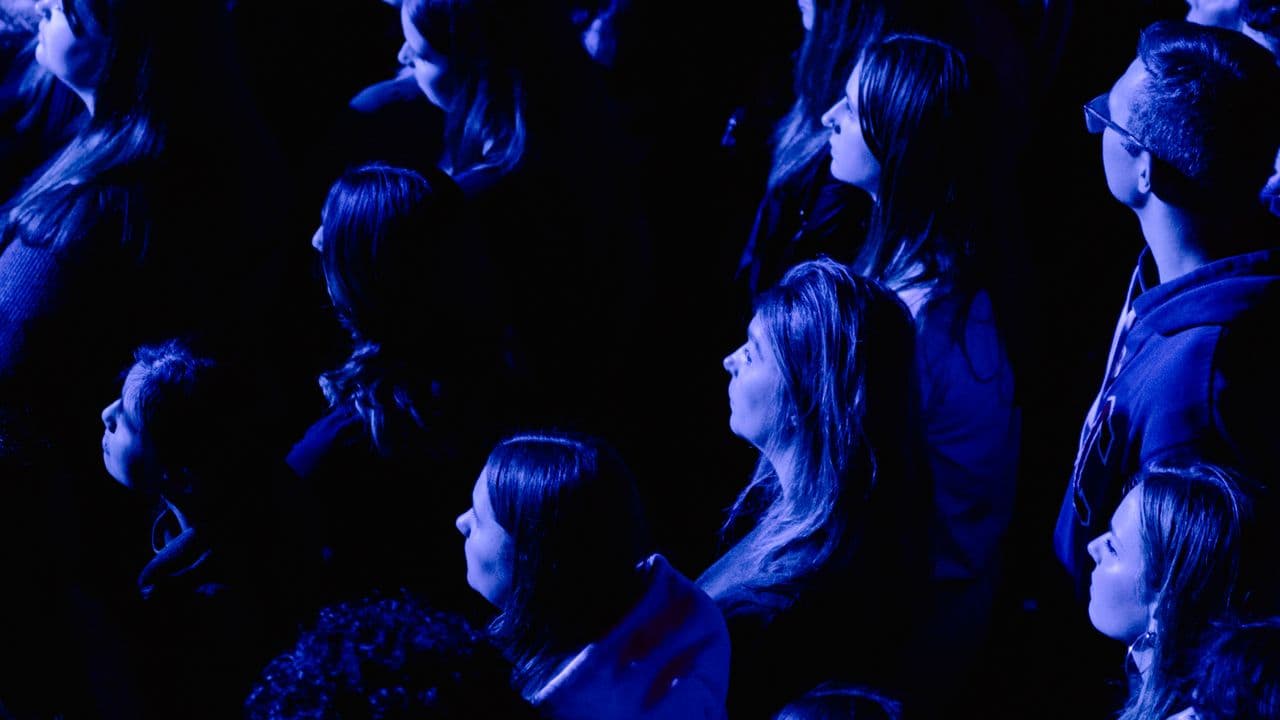 Foule de spectateurs devant une scène de concert éclairée par des projecteurs.