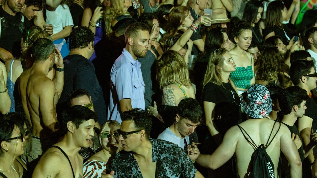 Foule rassemblée en plein air devant une scène de festival.