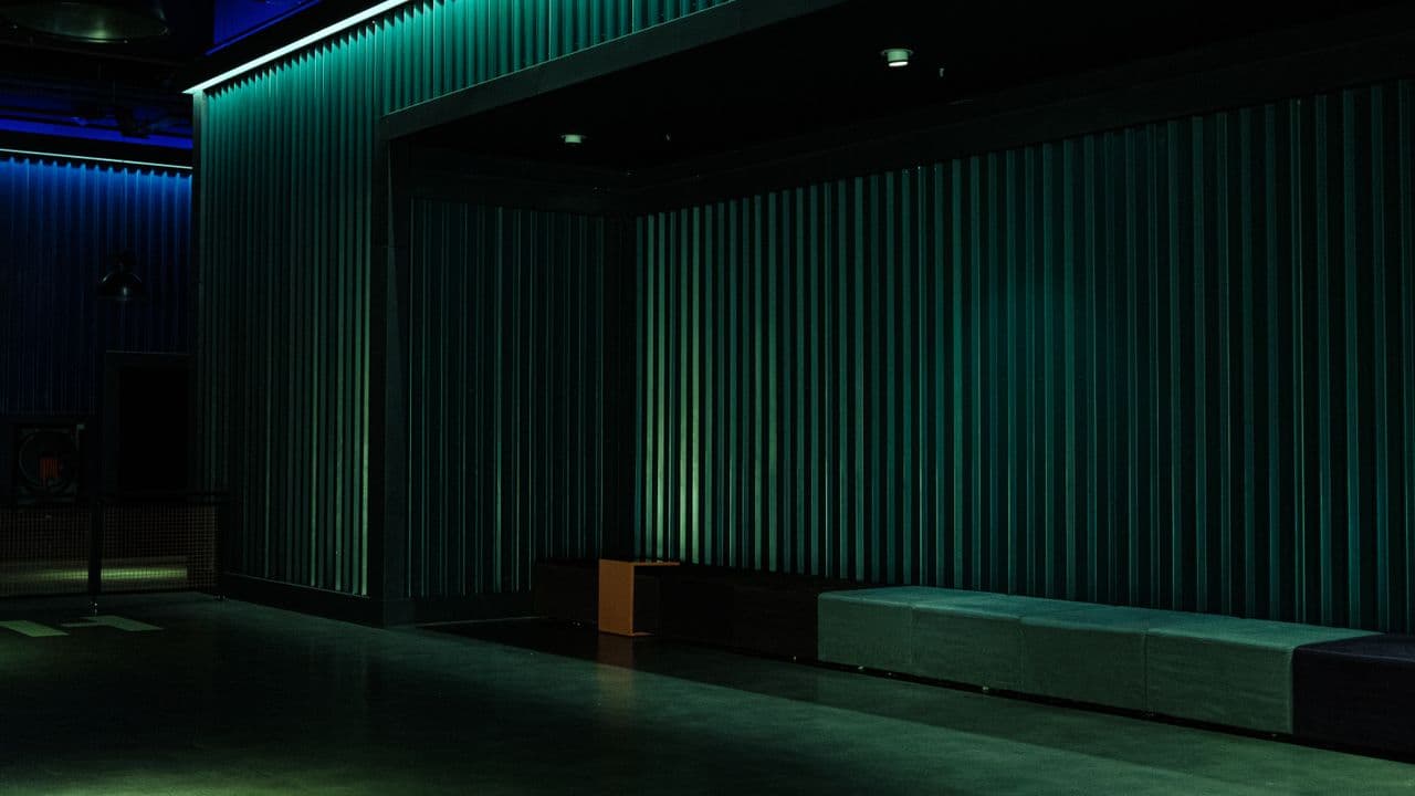 Salle de spectacle vue depuis les gradins, rideau et scène éclairés.