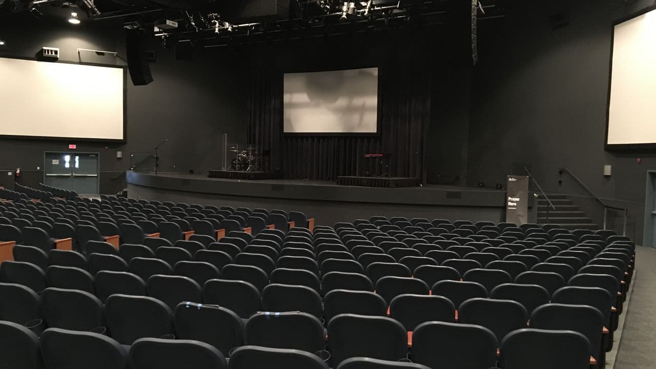 Scène de spectacle vide, éclairée par un projecteur.