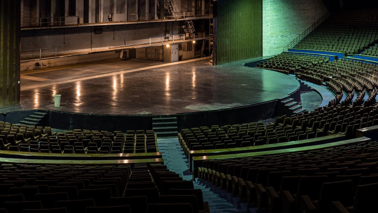 Projecteurs de théâtre dirigés vers une scène plongée dans la pénombre.