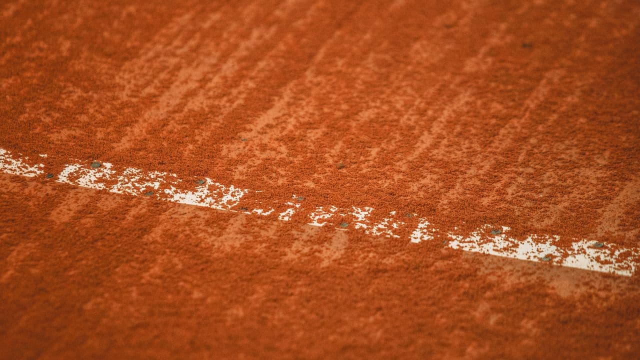 Court de tennis en terre battue vu de haut.